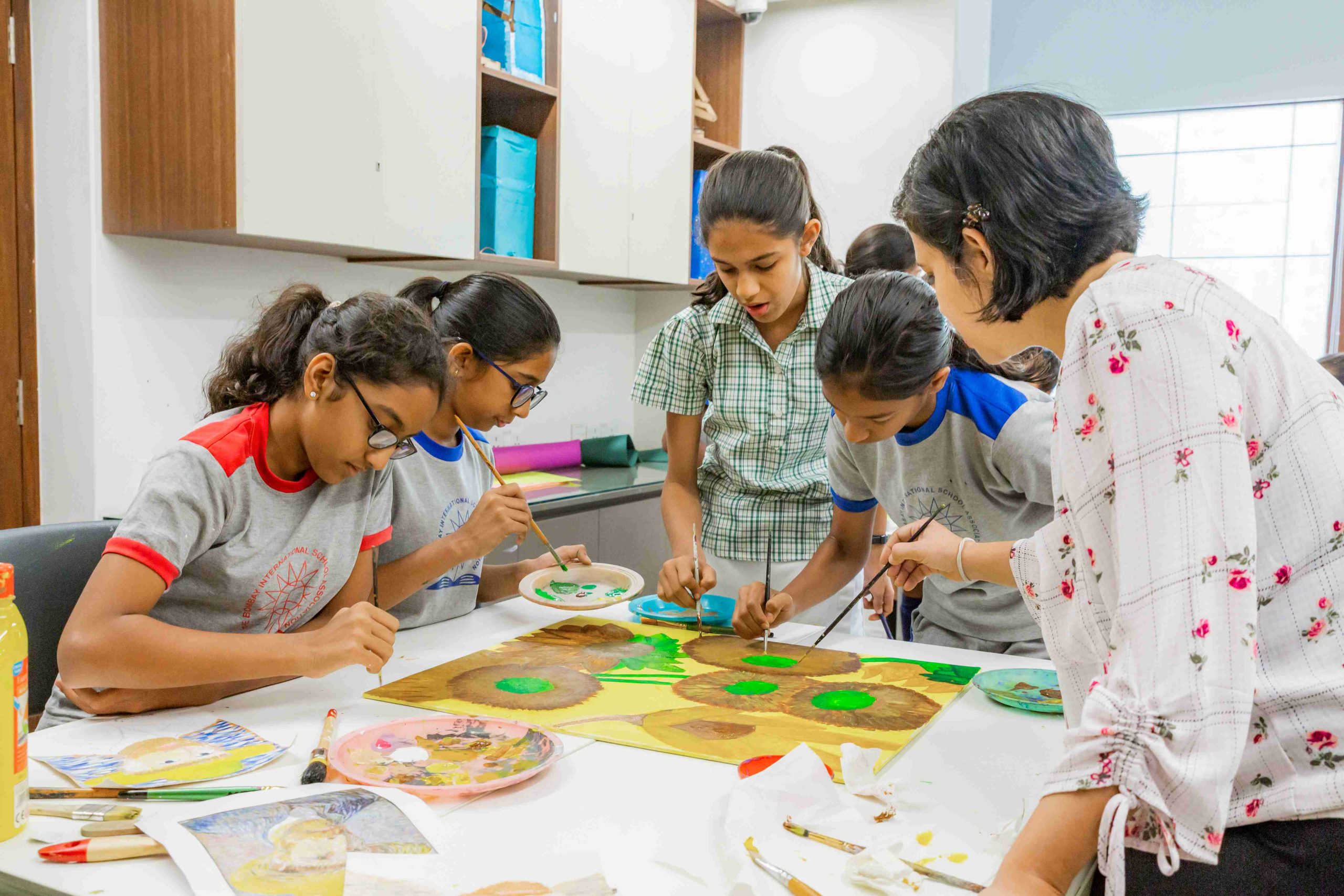 children surrounded around a table painting their canvases