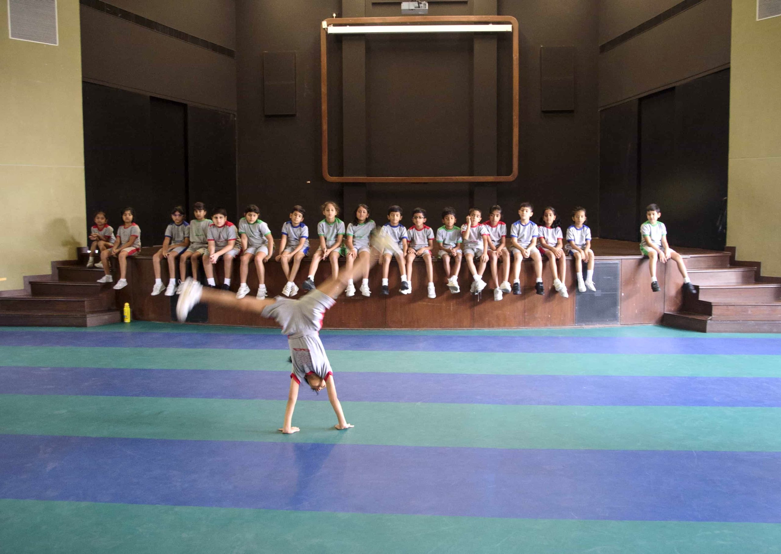 a girl doing cart wheel while rest all the class watching her from distant